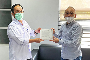 A local staff member presenting a donation certificate to a Vice President of Syiah Kuala University