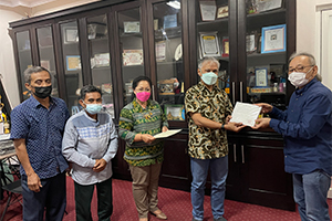 A grant certificate being presented to Vice President Dr. Ir. Encik of Mulawarman University